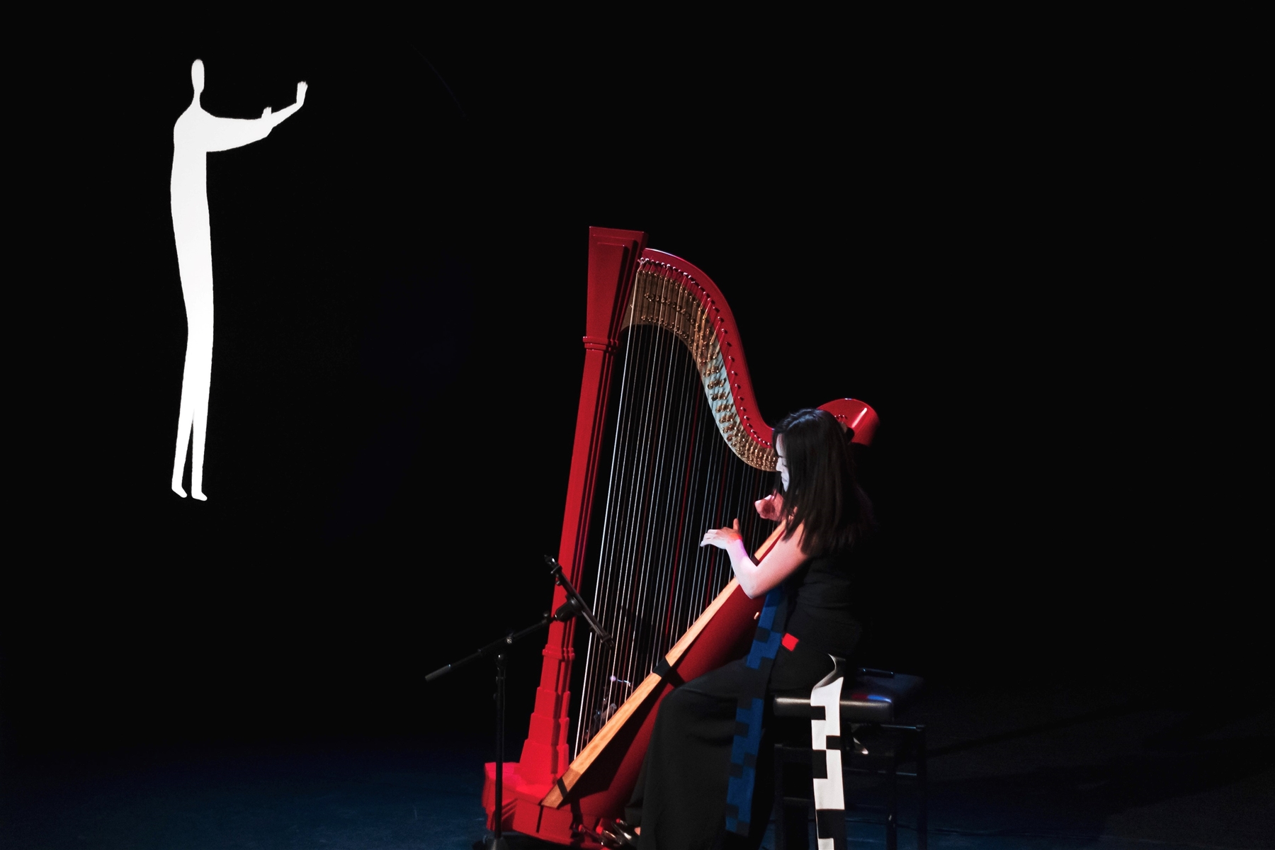 Lavinia Meijer speelt harp in een theatrale setting